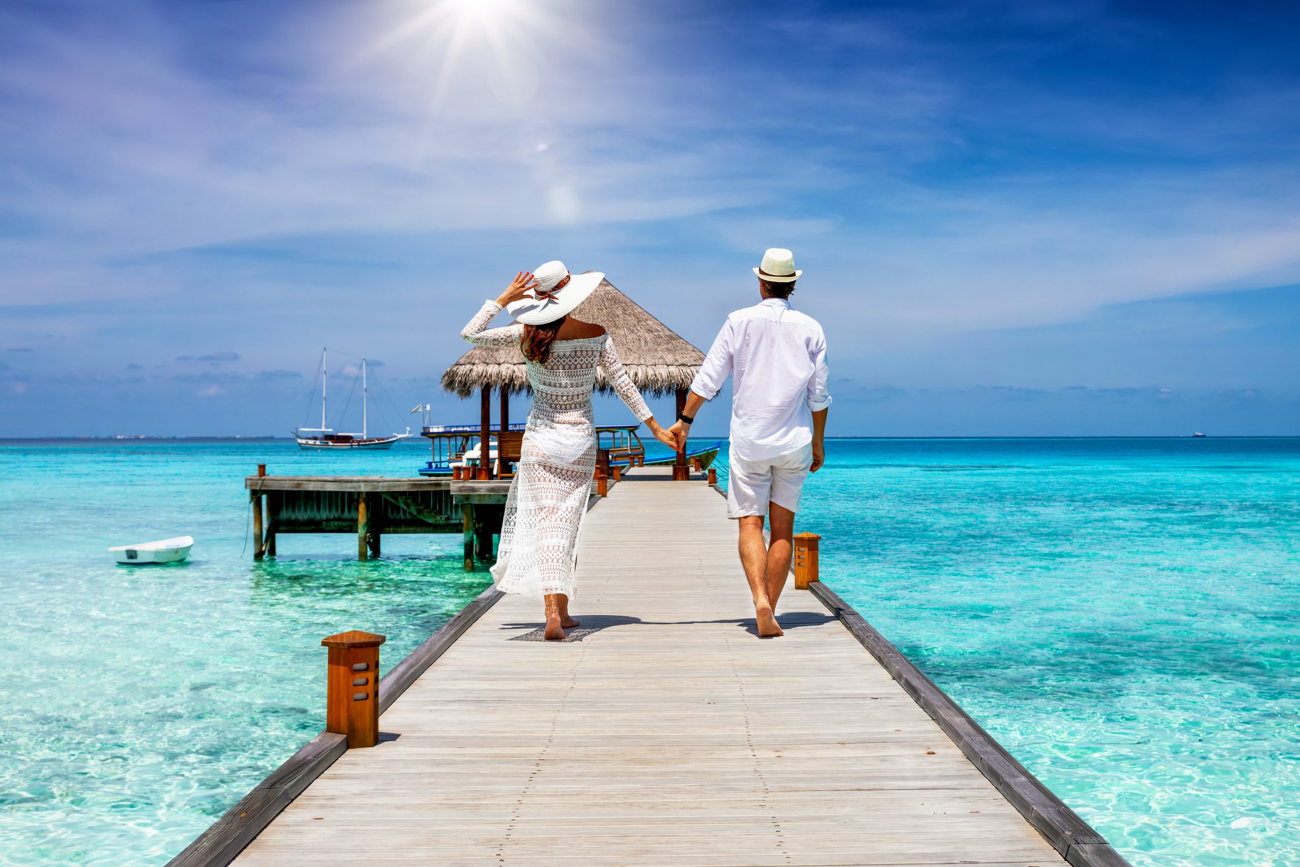 A happy couple in white summer clothing on vacation walks along